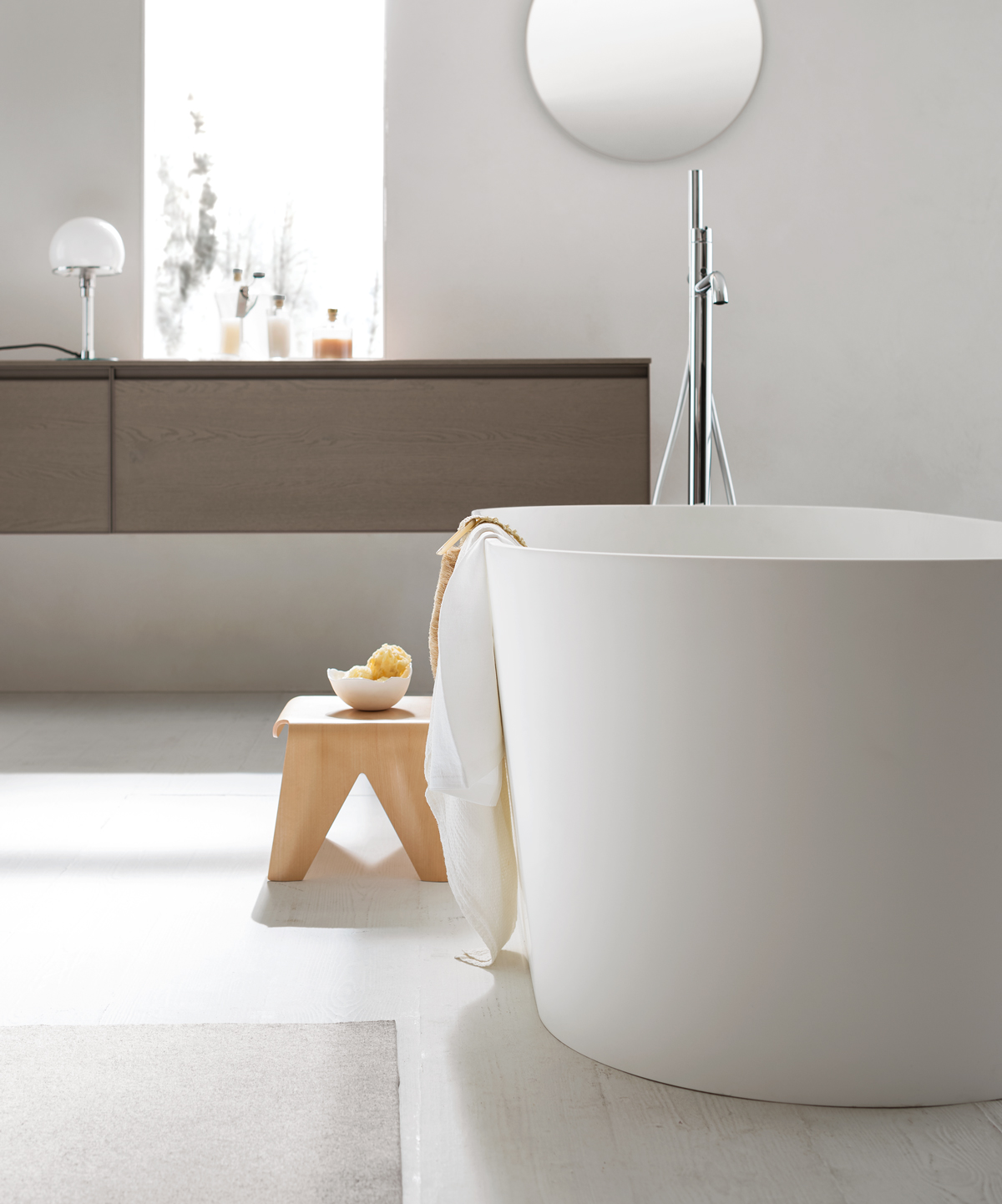 vasca freestanding bianca dalle forme tonde in bagno nordico con sgabellino in legno chiaro