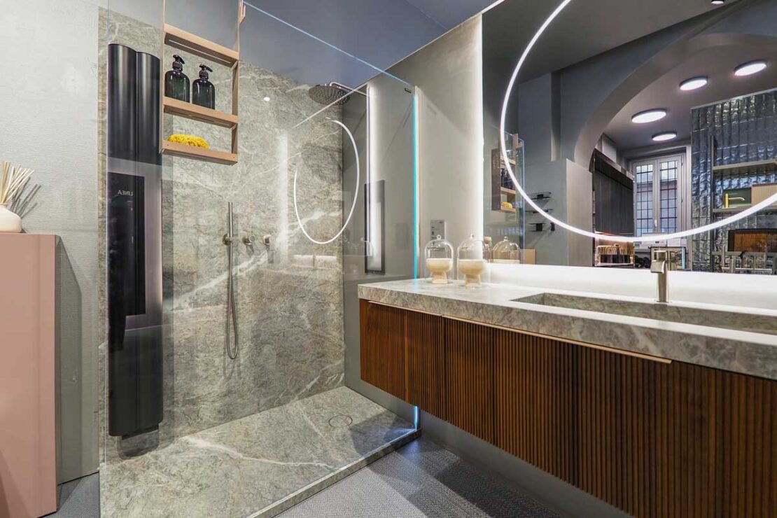 bagno moderno materico con piatto e pareti doccia coordinate al top con vasca integrata in finitura effetto pietra Marazzi Fior di Pesco